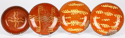 FOUR SLIP DECORATED REDWARE PLATES,