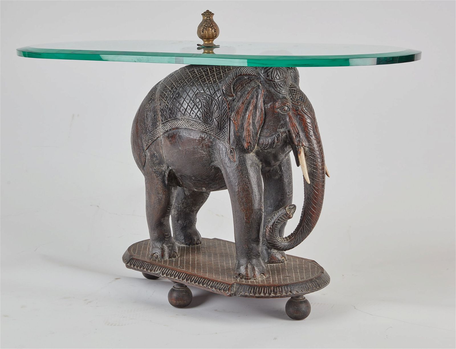 AN INDIAN HARDWOOD AND GLASS ELEPHANT