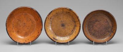 Three redware bowls: one with orange/yellow