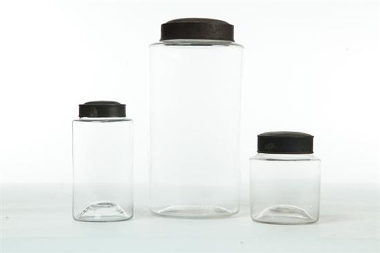 THREE GLASS STORAGE JARS WITH TIN LIDS.