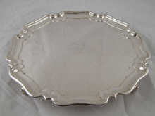 A silver salver with scroll feet and