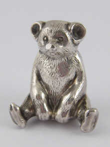 A silver seated teddy bear pin