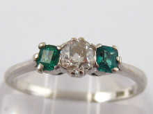 A three stone diamond and emerald ring