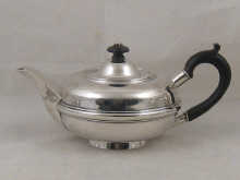 A silver teapot of flattened globe