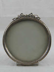 A circular silver frame with ribbon