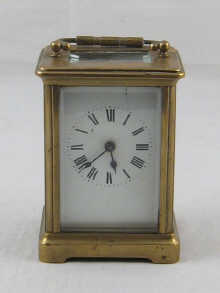A brass carriage clock with white enamel