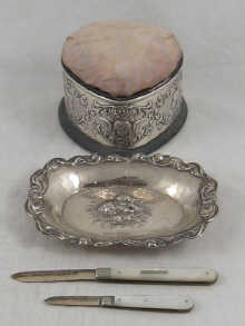 A silver heart shaped pincushion