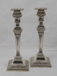 A pair of silver candlesticks the square