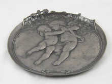 A circular pewter dish with putti and