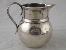 A silver cream jug with sparrow