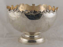 A silver punch bowl with scrolling rim
