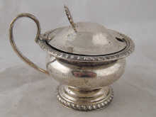 A silver mustard pot with blue