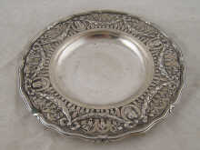 A circular dish in white metal