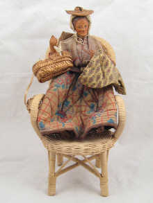 A peddlers doll seated in wicker chair