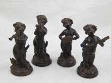 A set of four black ceramic putti playing