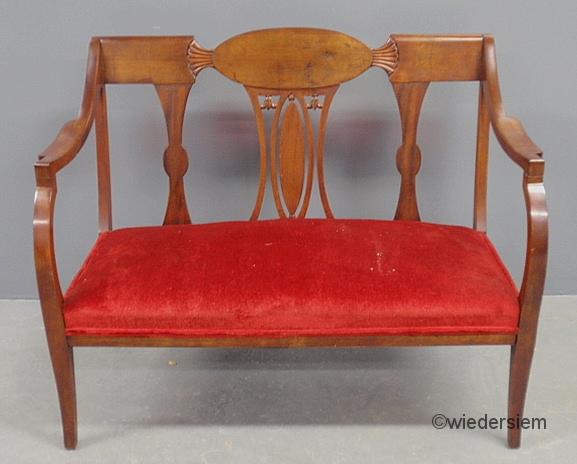 Cherry stained settee with a red upholstered