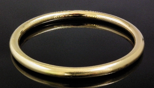 A gold coloured metal stiff bangle 15b838