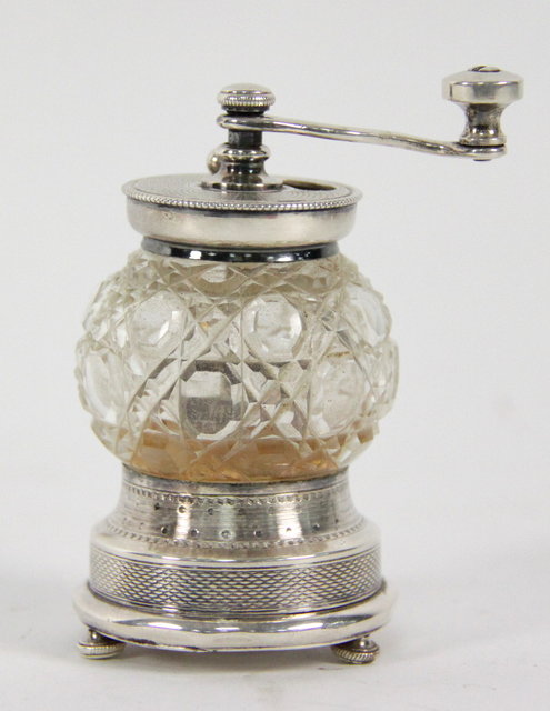 A cut glass pepper mill with plated