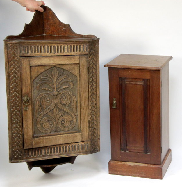 A corner cupboard with carved door and