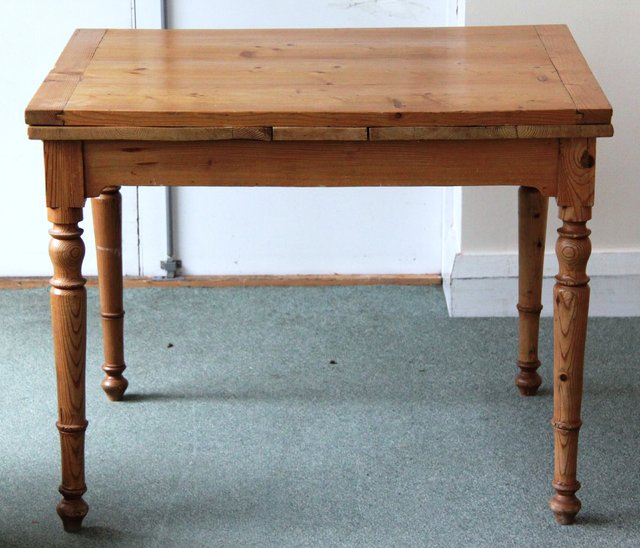 A pine dining table with a drawer on