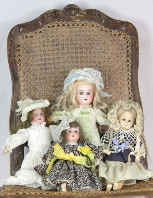 A small bisque head doll and three others