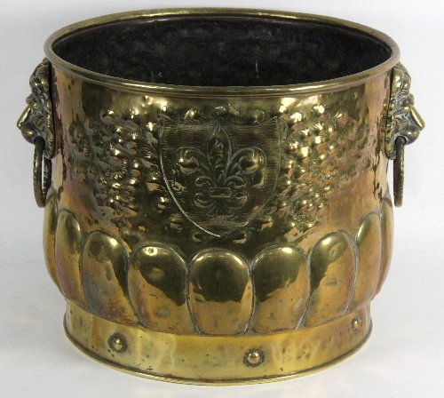 A circular embossed brass bucket with