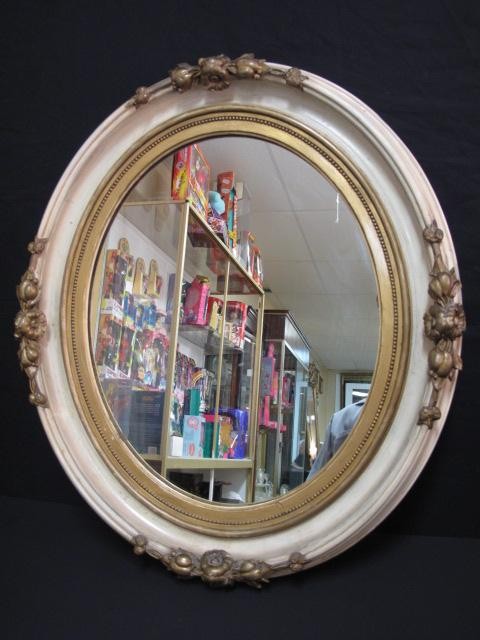 Oval wall mirror with floral motif.