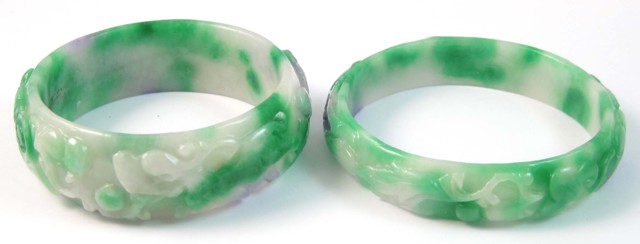 TWO CARVED JADE BANGLES. Both round
