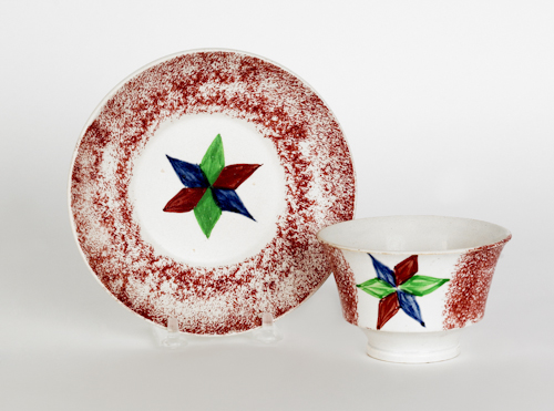 Red spatter cup and saucer with a star