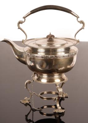A circular silver tea kettle and