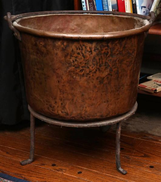 A LARGE RUSTIC COPPER KETTLE ON IRON