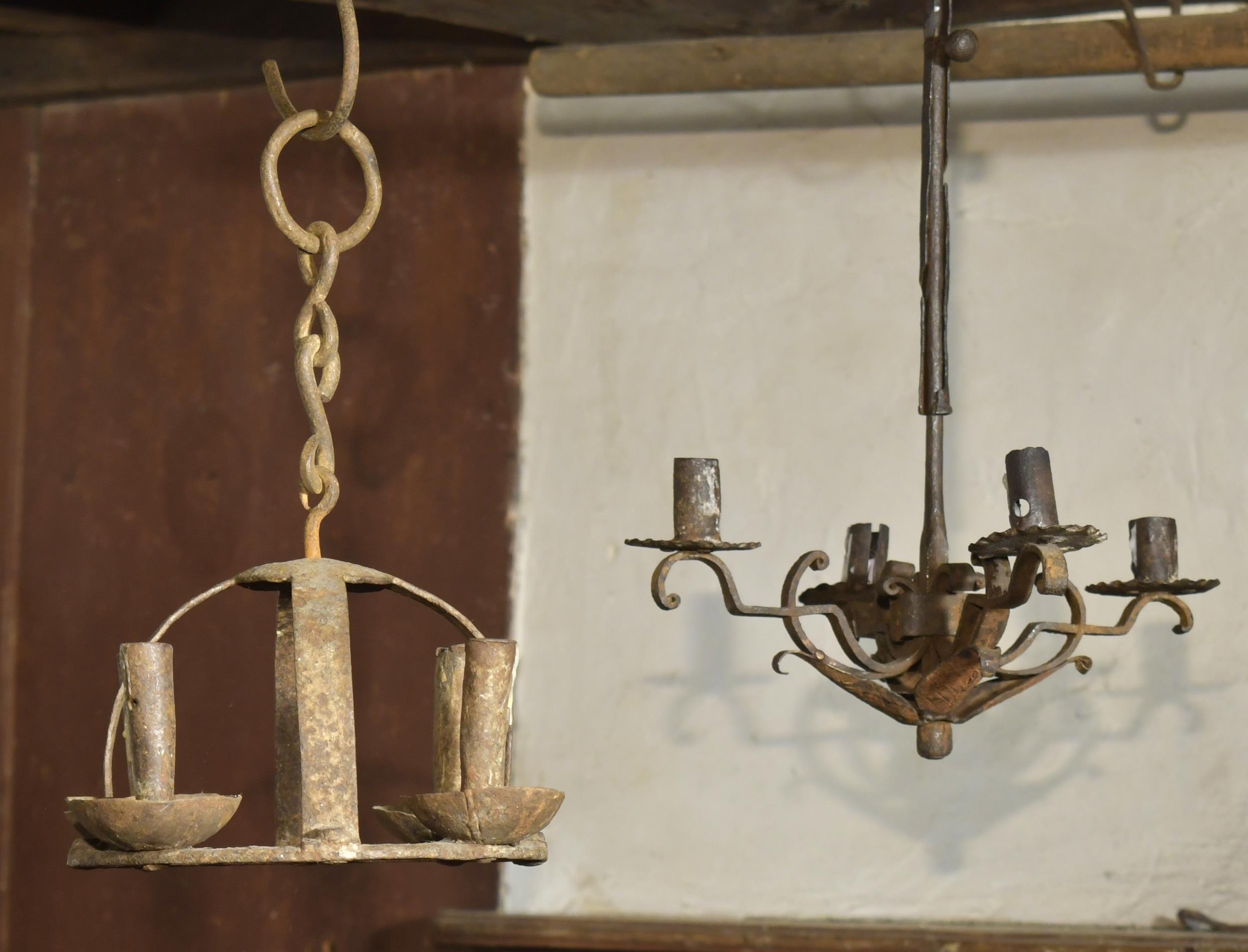 TWO EARLY IRON CHANDELIERS. A hand