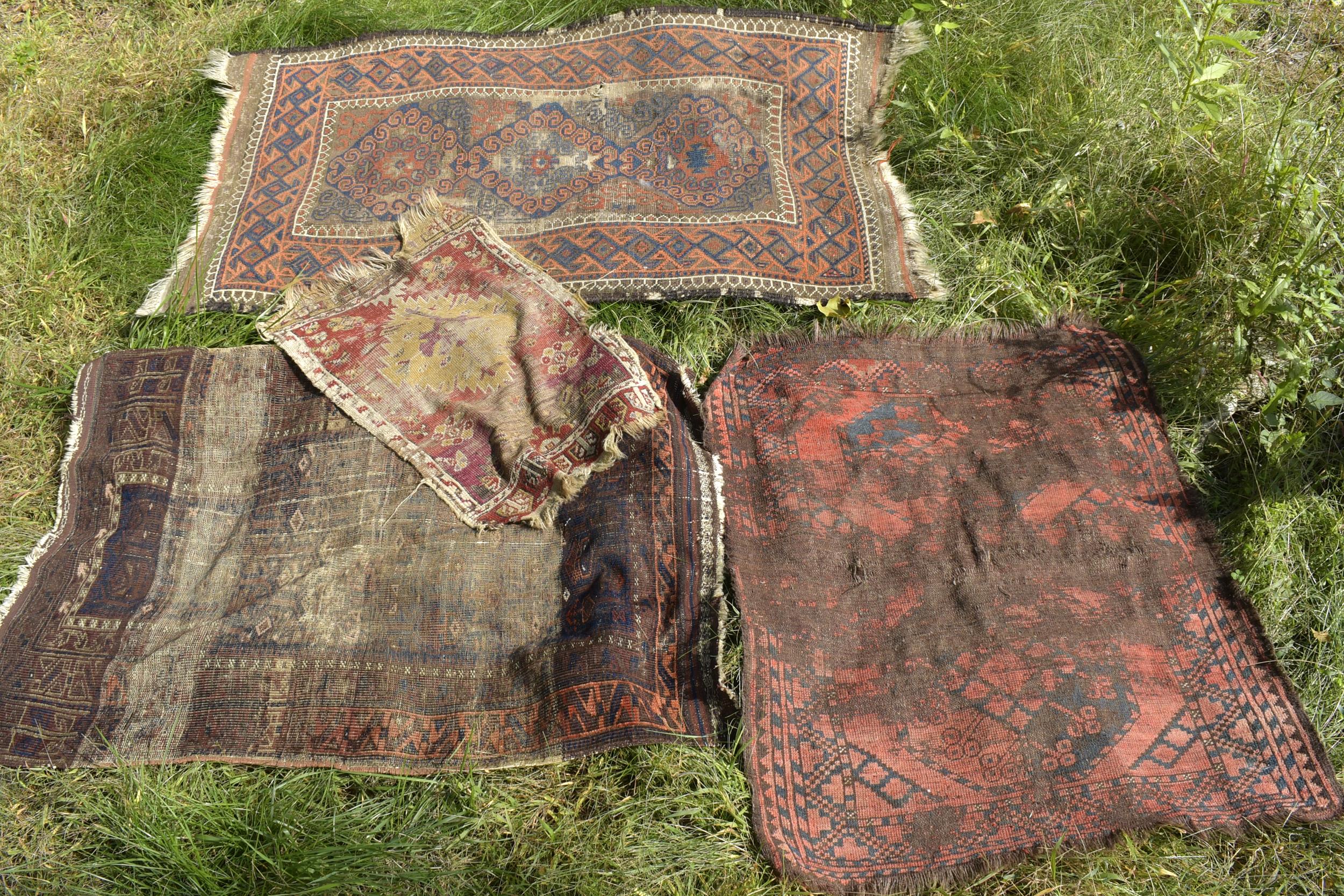 FOUR WORN ANTIQUE ORIENTAL RUGS.