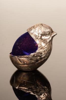 A silver coloured metal chick pin cushion,