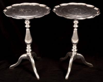 A pair of metal tripod tables with lobed