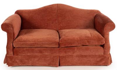 An upholstered camel back sofa
