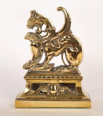 A brass door stop of griffin form, weighted,