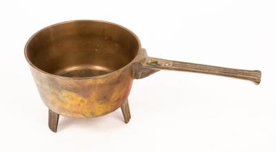 A brass skillet, the handle indistinctly