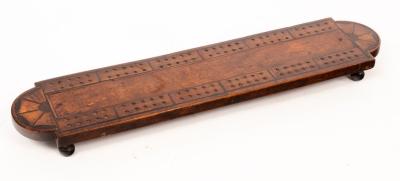 A fruitwood cribbage board, the rounded