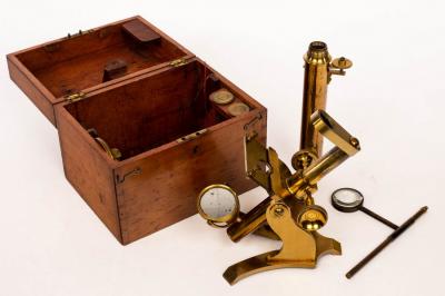 A small gilt brass microscope in fitted