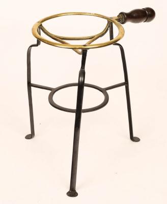 A wrought iron and copper trivet with