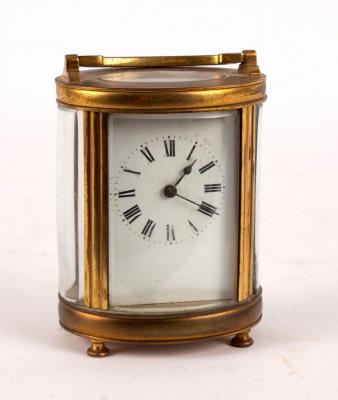 A carriage clock in an oval gilt brass