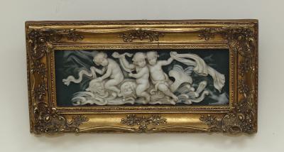 A resin plaque depicting putti riding