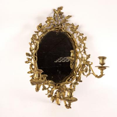 An oval wall mirror, the gilt brass