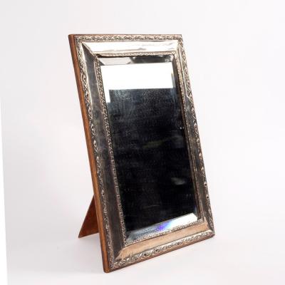 A silver framed mirror with easel