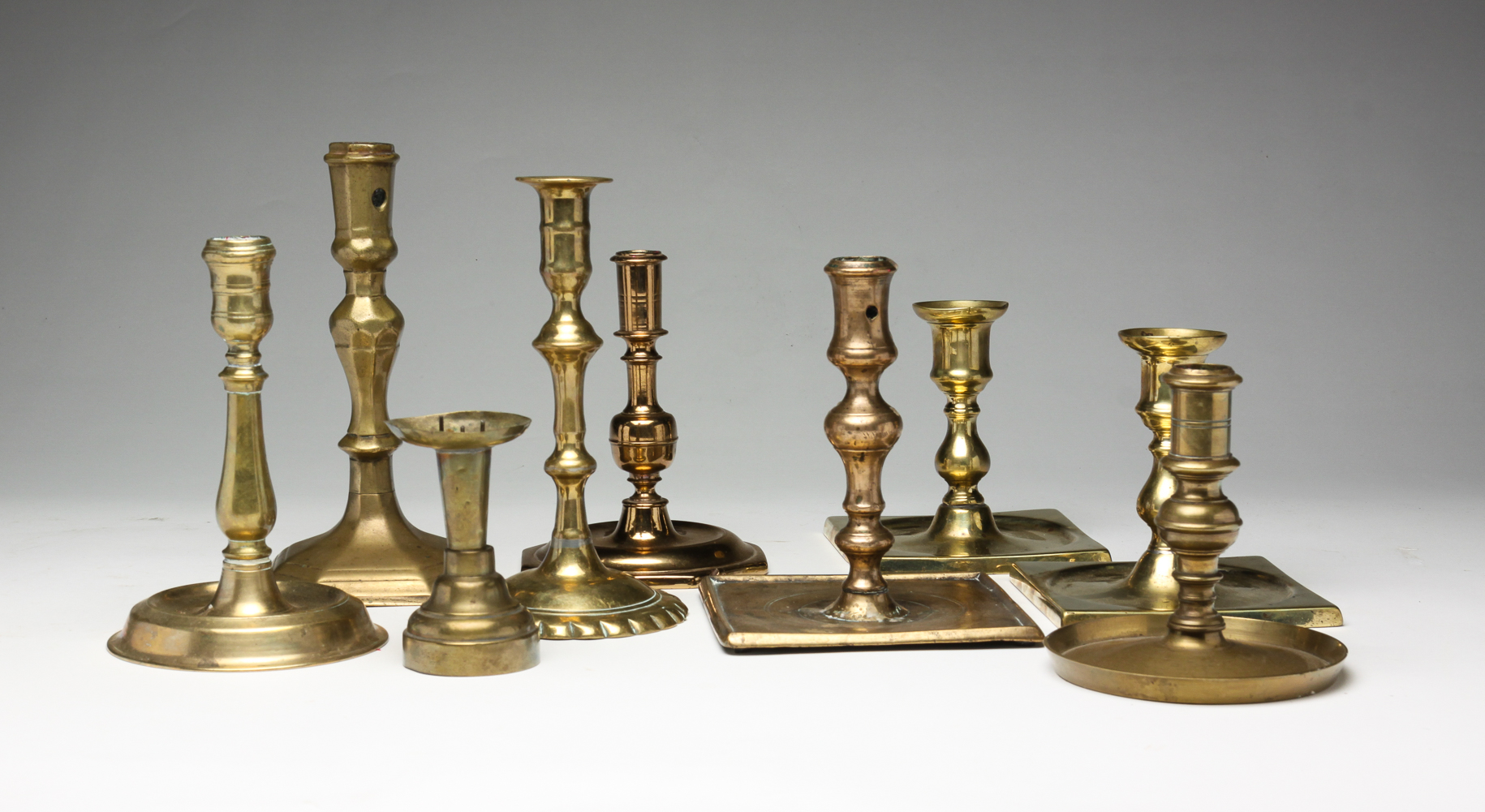 NINE EUROPEAN BRASS CANDLESTICKS.