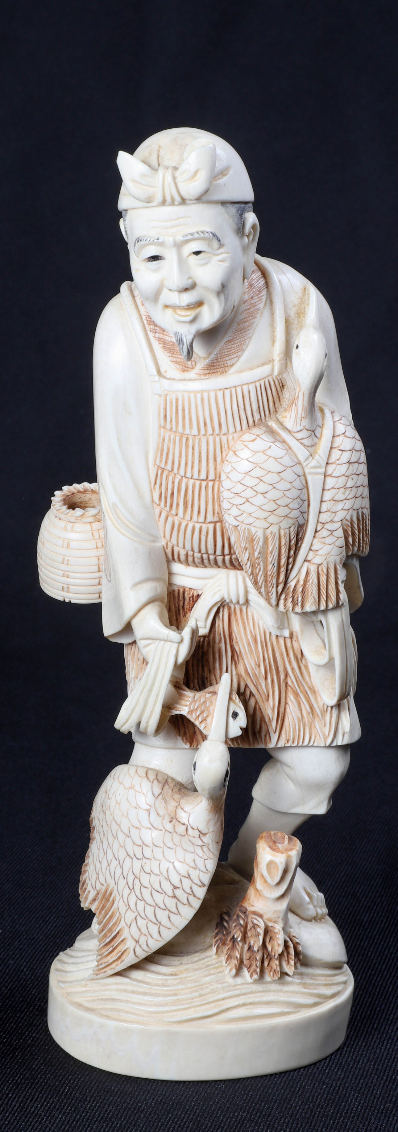 Carved ivory figure of a fisherman,