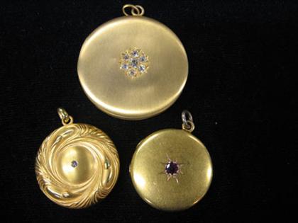 Three circular gold lockets etched with