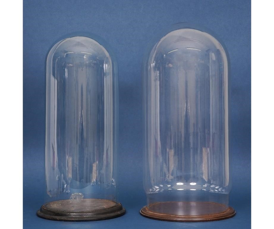 Two large glass domes on wooden bases.
Both