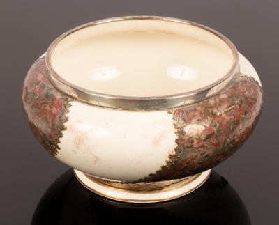 A ceramic bowl with a silver rim, decorated